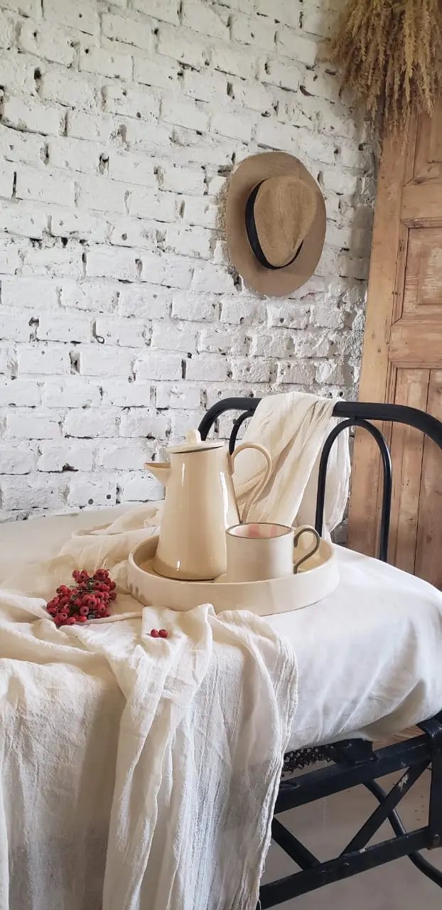 Cafetera, taza y bandeja en tono crudo sobre una silla de hierro