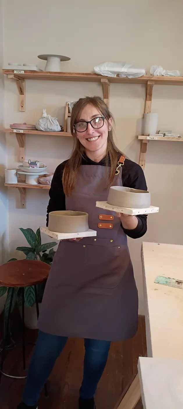 Una alumna feliz mostrando los dos cuencos que modeló