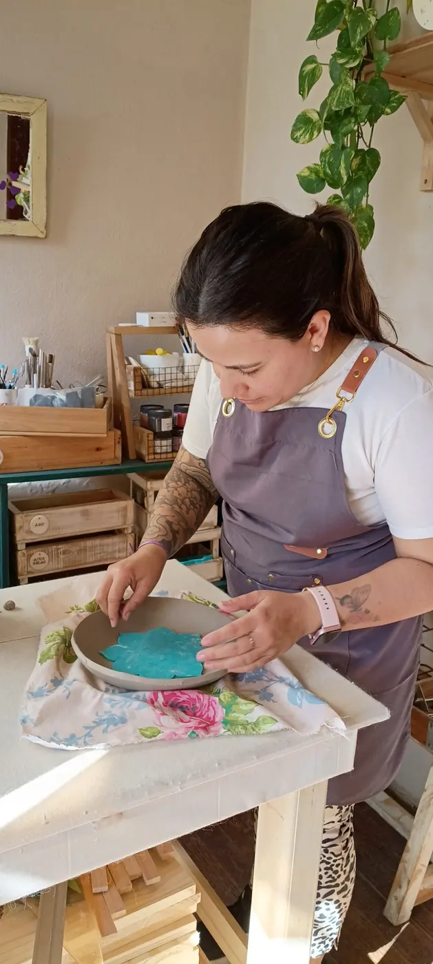Una alumna decorando un plato con una flor de color turquesa