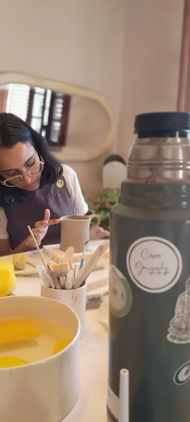 Una alumna modelando una jarrita, junto a un termo con el sticker de Casa Gonzalez